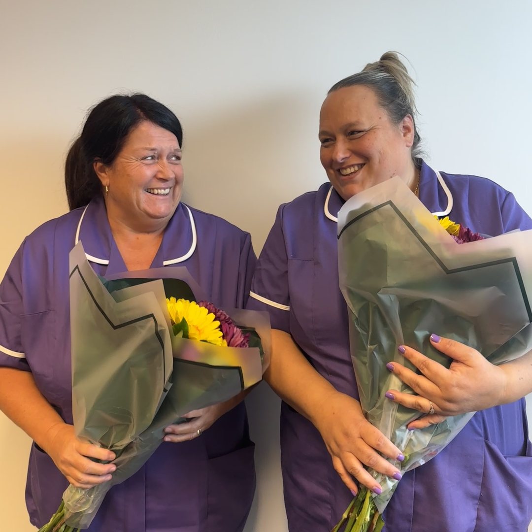 Two of our care workers with flowers, celebrating ten years with Above & Beyond Care
